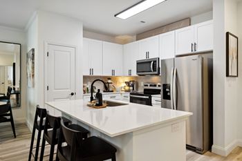 a kitchen with a large white island and stainless steel appliances